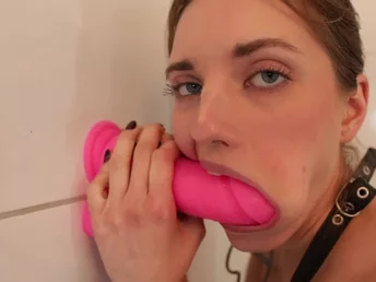 Teen whore is blowing a monstrous pink intercourse fucktoy that's stuck to a wall
